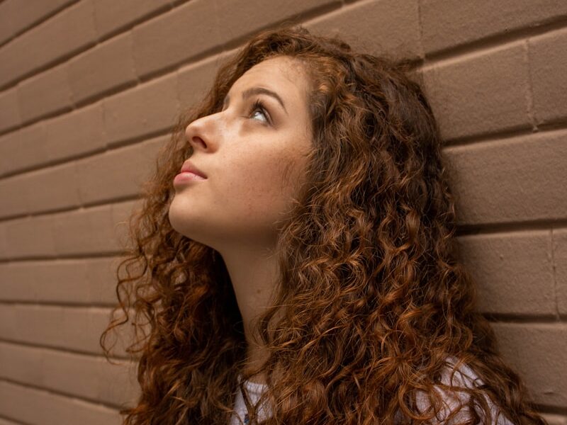 woman in white shirt standing beside brown wall