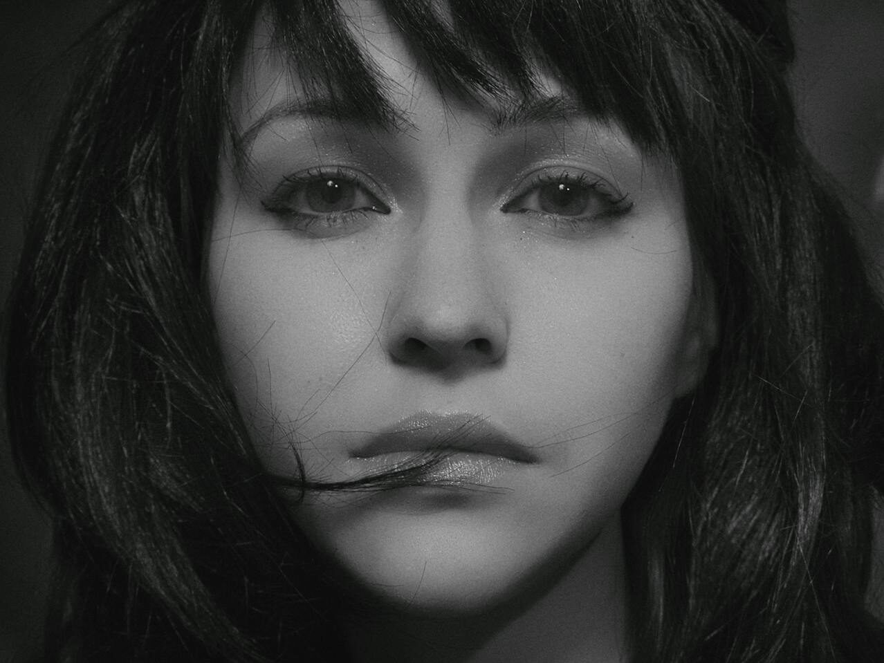 Emotive black and white portrait capturing a woman's thoughtful expression in a studio setting.