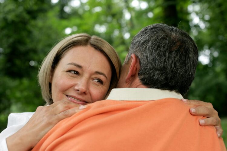 Close-up of a mature couple sharing a loving embrace in a serene outdoor setting.