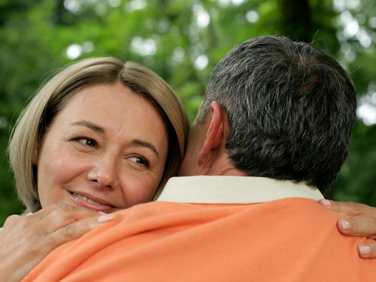 Close-up of a mature couple sharing a loving embrace in a serene outdoor setting.