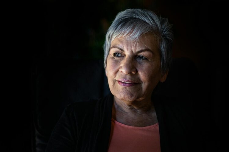 Elderly woman with gray hair looking thoughtfully, showcasing wisdom and grace.