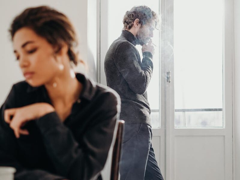 A couple experiencing tension and introspection indoors with a bright window.