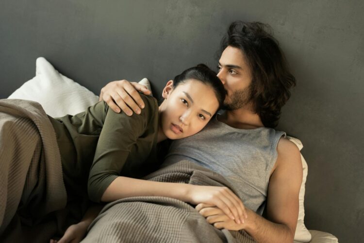 Romantic couple embracing on a bed, showcasing love and togetherness in a cozy setting.