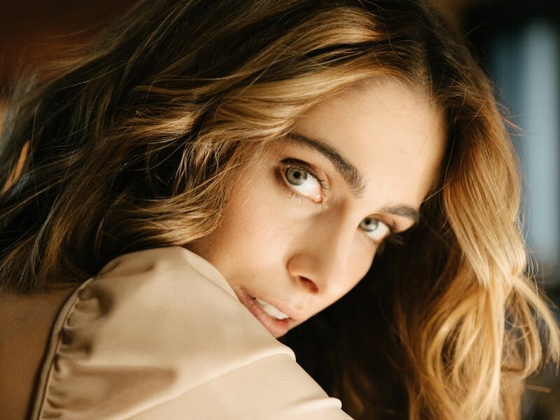 Captivating portrait of a woman with wavy hair, looking over her shoulder indoors.