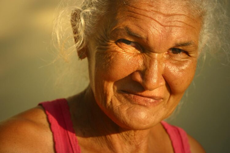 Portrait of an elderly woman smiling warmly in the golden light of sunset.