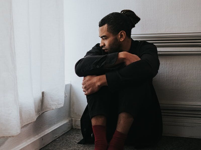 Thoughtful man sitting alone by a window, contemplating indoors.