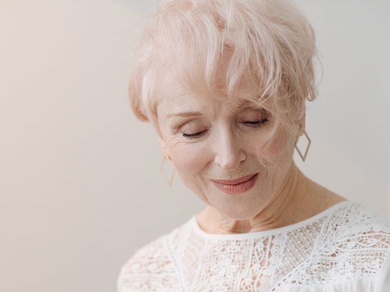 Elegant senior woman with white hair reading a magazine, captures grace and relaxation.