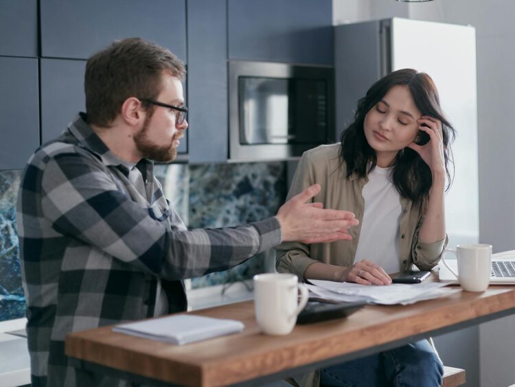 A couple engaging in a serious conversation in their kitchen, showcasing relationship dynamics.