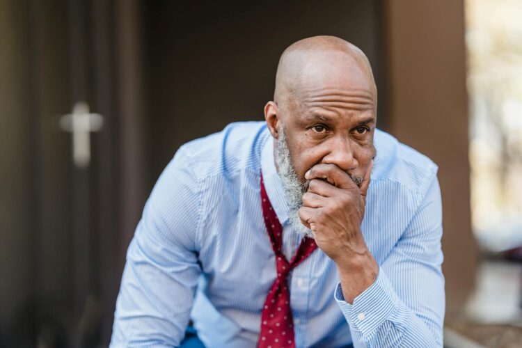 Thoughtful middle-aged man in business attire sitting outdoors, pondering solutions to a problem.