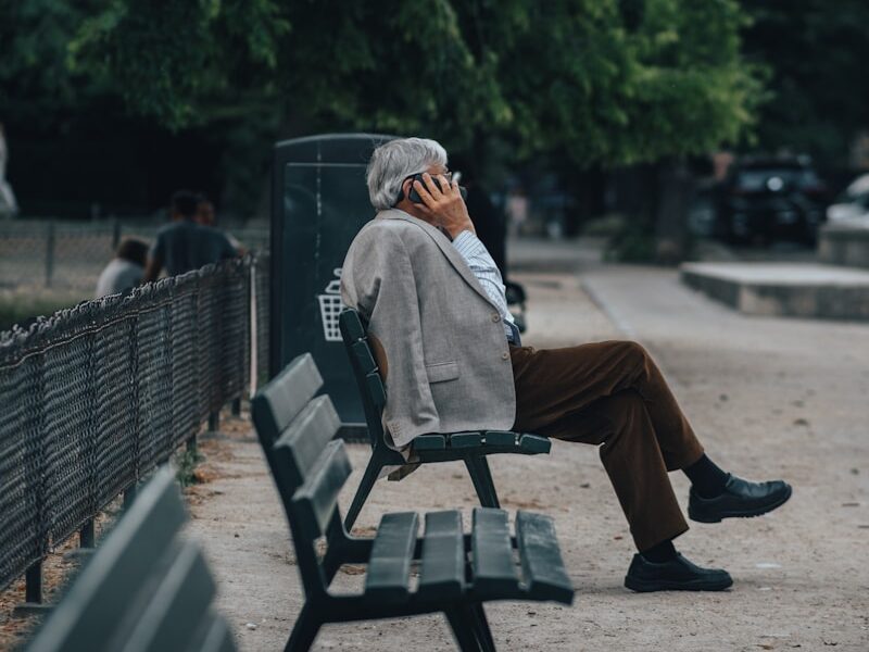 man in brown jacket sitting on bench