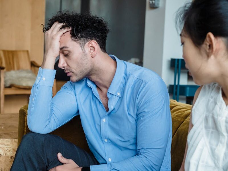 A couple sitting indoors, showing emotional stress and tension during a quarrel.