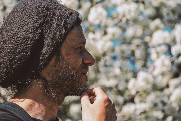 man in black and white knit cap smoking cigarette during daytime