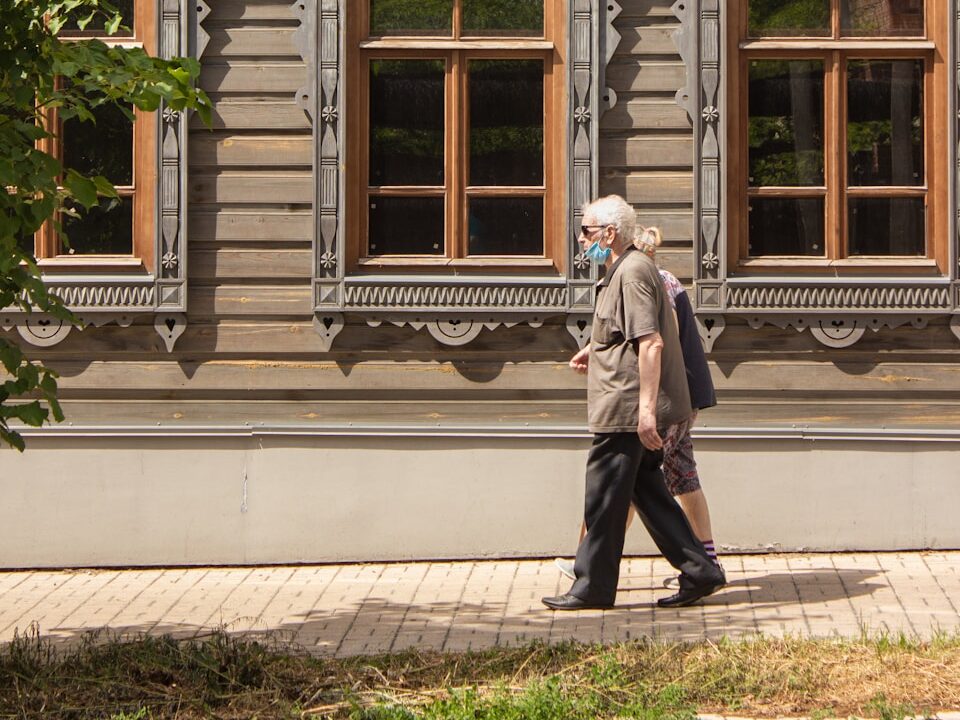 woman in gray coat standing in front of white wooden window