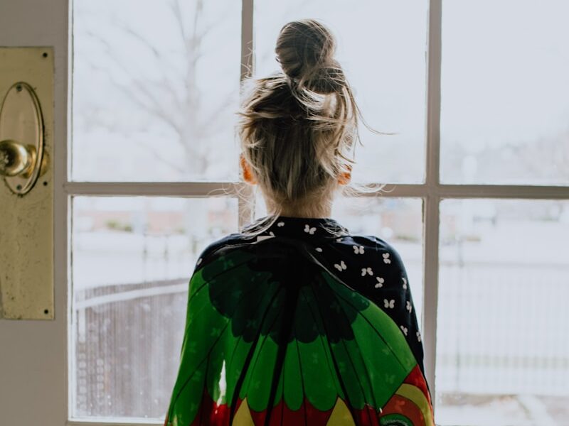 woman in green orange and yellow dress standing near window