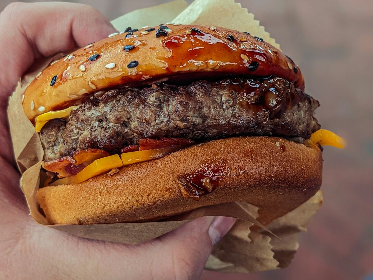 a person holding a hamburger in their hand