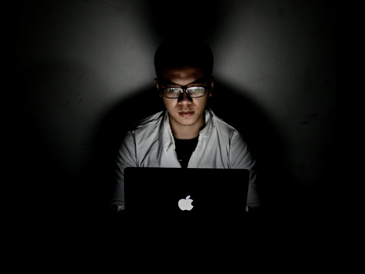 man using MacBook inside dark room
