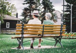 man and woman sitting on brown wooden bench during daytime