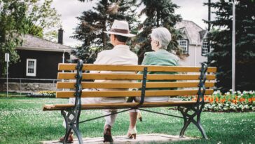 man and woman sitting on brown wooden bench during daytime