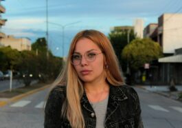 a woman with glasses standing on the side of the road