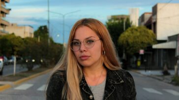 a woman with glasses standing on the side of the road