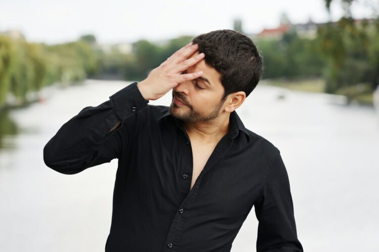 a man in a black shirt holding his hands to his head