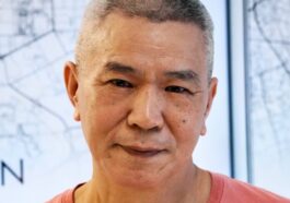 A man in a red shirt standing in front of a map