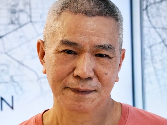 A man in a red shirt standing in front of a map