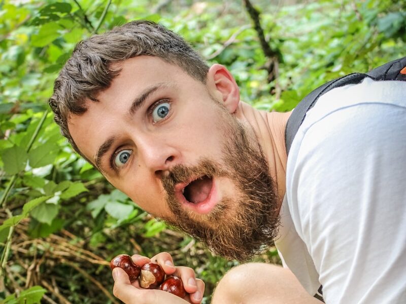 A man in a white shirt is eating a berry