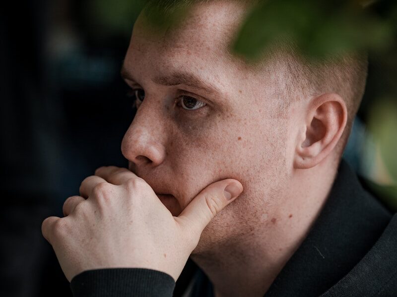 man in black jacket covering his mouth