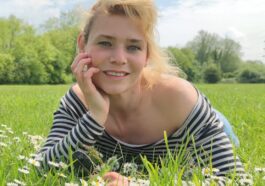 woman in black and white striped shirt lying on green grass field during daytime