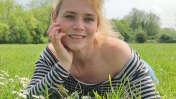 woman in black and white striped shirt lying on green grass field during daytime