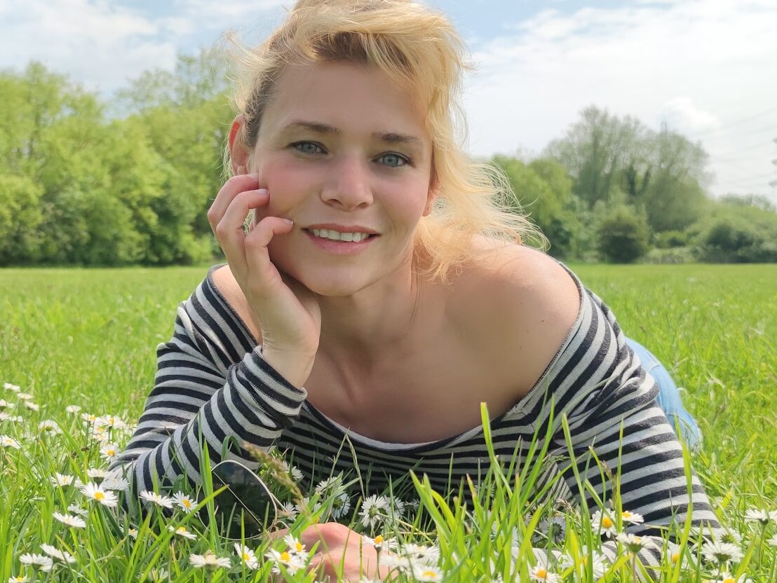 woman in black and white striped shirt lying on green grass field during daytime