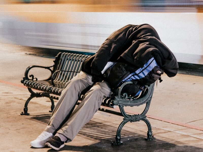 person sleeping on black steel bench