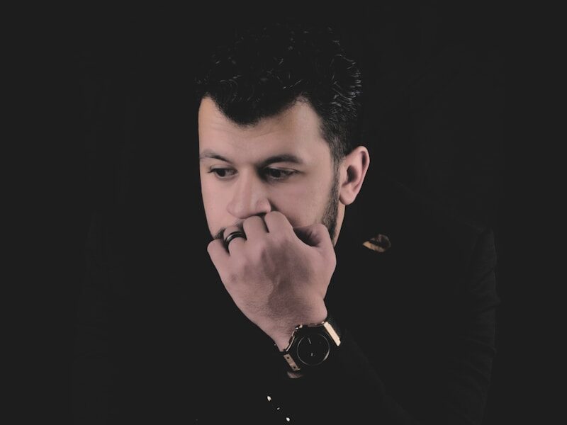 a man in a black shirt holding his hand to his mouth