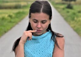 a woman in a blue dress holding a cigarette