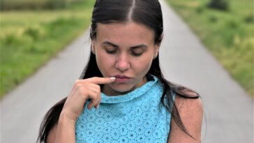 a woman in a blue dress holding a cigarette