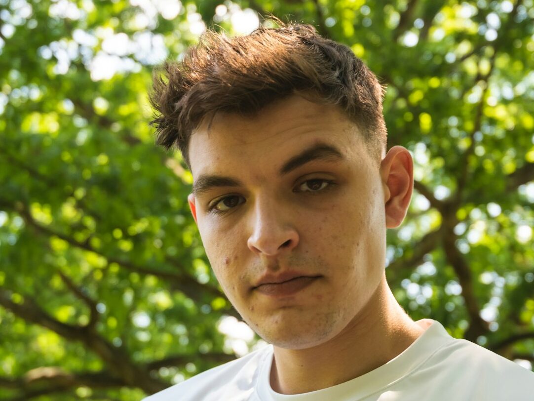 a young man standing in front of a tree