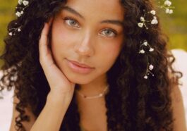 Portrait of a woman with curly hair and flowers outdoors in spring.