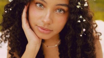 Portrait of a woman with curly hair and flowers outdoors in spring.