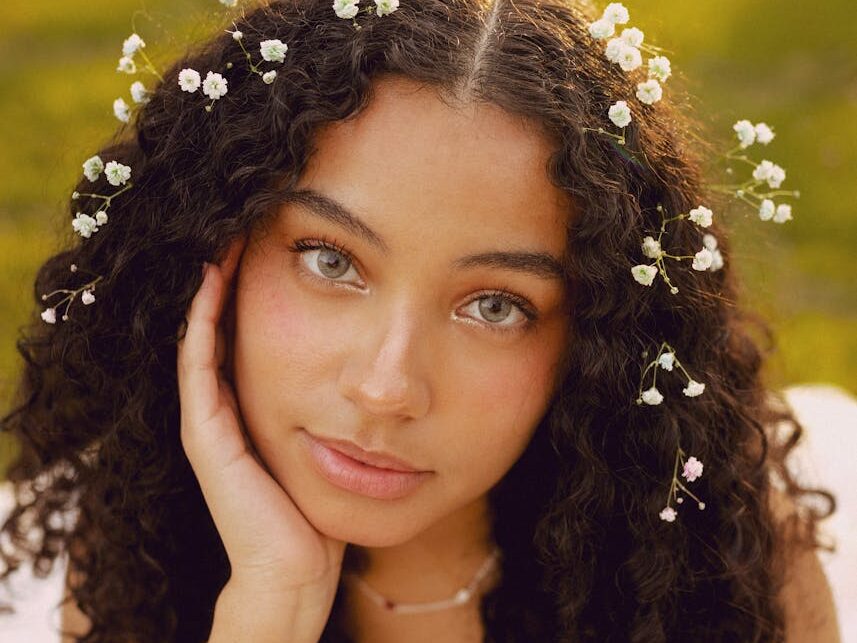 Portrait of a woman with curly hair and flowers outdoors in spring.