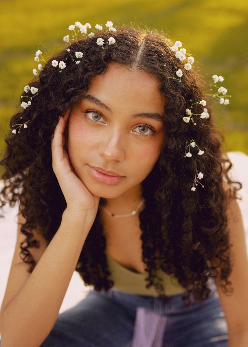 Portrait of a woman with curly hair and flowers outdoors in spring.