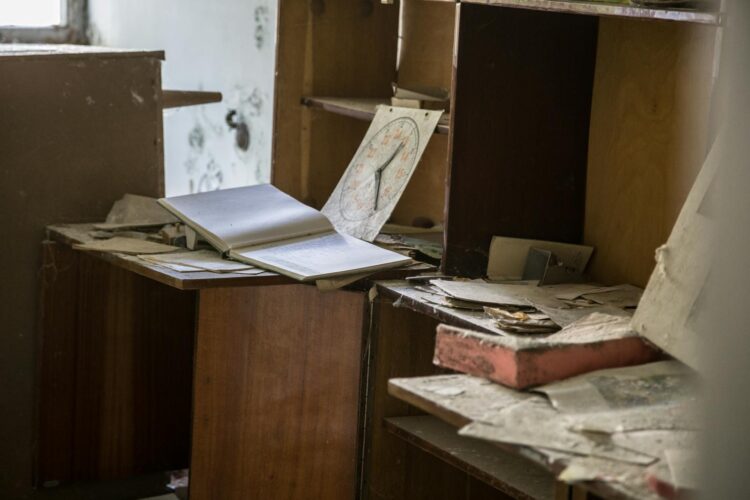A cluttered, dusty office with open books, papers, and shelves, evoking a rustic and abandoned feel.