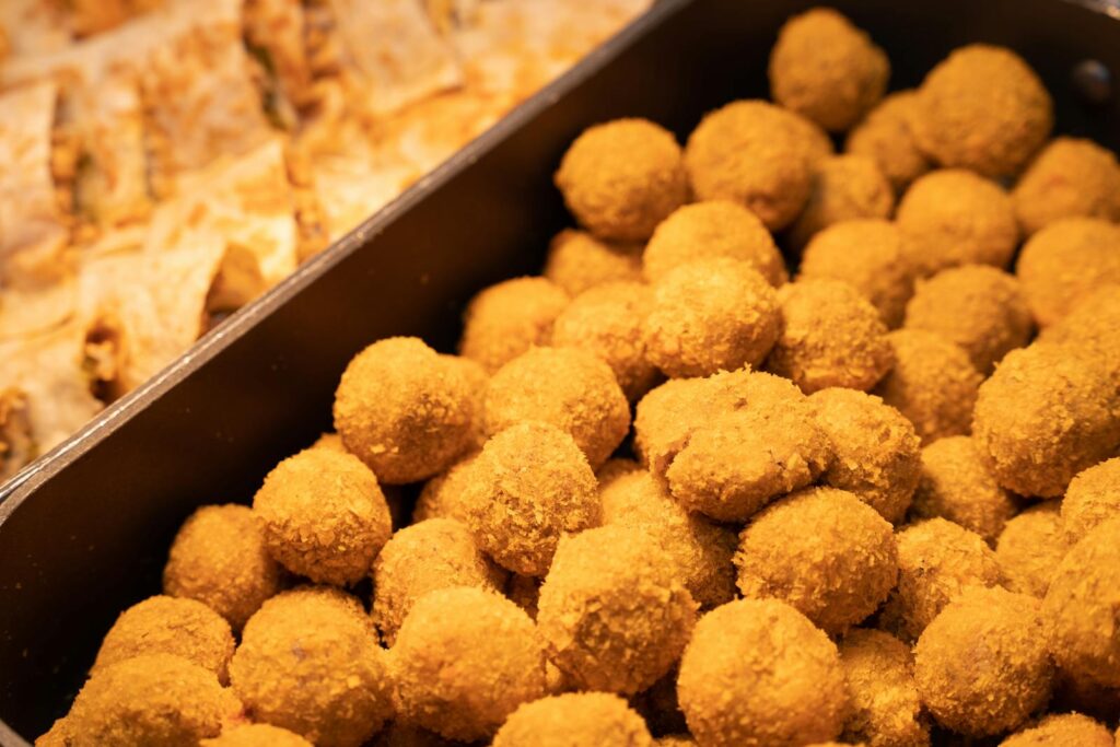 Close-up of crispy golden nugget balls in a serving tray, perfect for food photography.