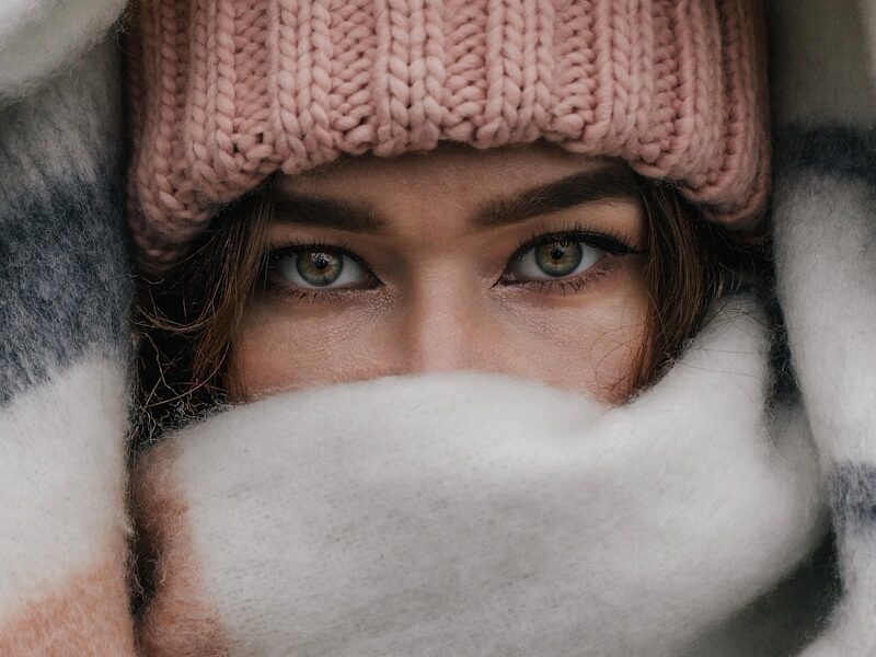 a woman with blue eyes hiding under a blanket