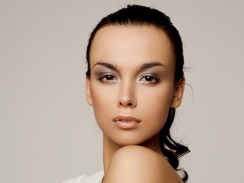 Graceful portrait of a woman in a white shirt, exhibiting a serene and confident expression in a studio setting.