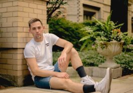 Young man in casual wear sitting on pavement outdoors, Chicago suburb vibe.