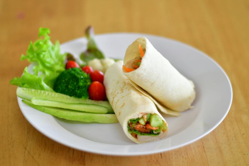 Delicious veggie wraps with fresh vegetables on a white plate, perfect for a healthy lunch.