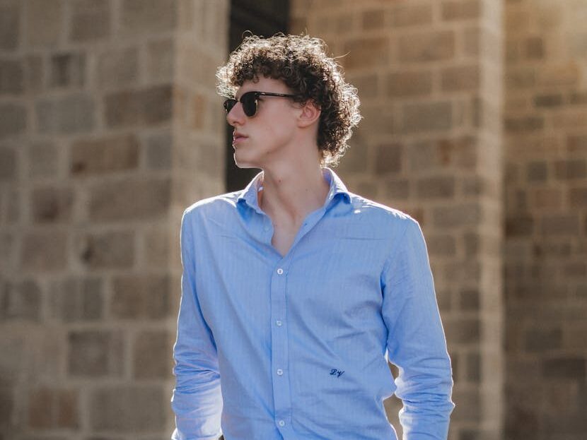 Portrait of a fashionable man in sunglasses against a stone wall in Barcelona.