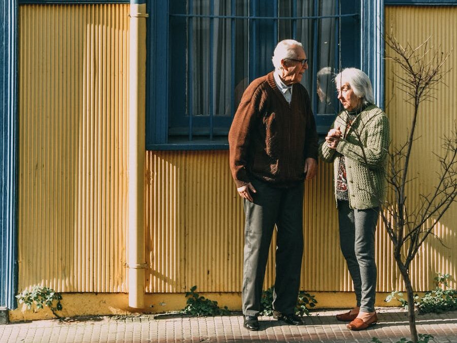 A senior couple standing in front of a colorful building in Valparaíso, enjoying the sunny day.