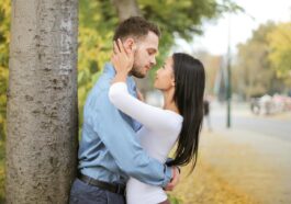 A romantic couple embracing by a tree in a vibrant autumn setting.